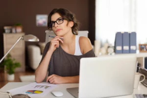 Mujer pensativa frente a una computadora portátil, analizando gráficos financieros para calcular el valor de su empresa