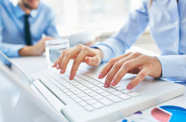 Manos de una mujer escribiendo en un teclado de computadora portátil durante una reunión de negocios