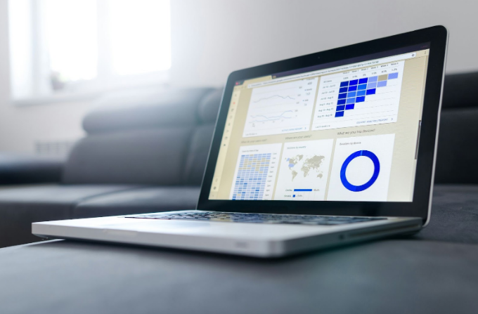 Computadora portátil mostrando análisis de datos y gráficos en pantalla, en ambiente de oficina