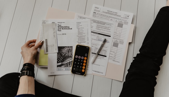 Persona revisando documentos fiscales, facturas y constancia de retención de impuestos junto a una calculadora
