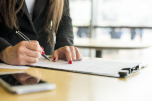 Mujer firmando documento en oficina, relacionado con trámites fiscales y constancia de situación fisca