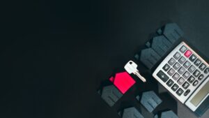 Calculadora, llave y casas en miniatura sobre fondo negro