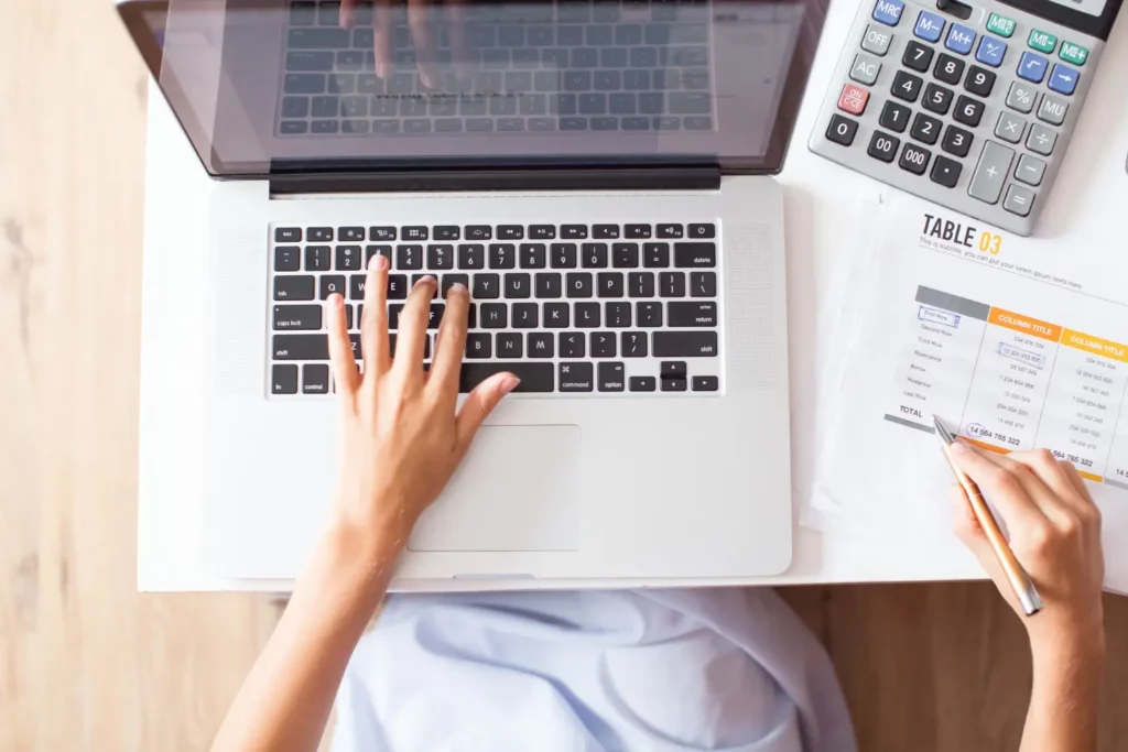 Persona capturando datos de facturación en una laptop mientras revisa cálculos de CFDI 4.0 y anticipos