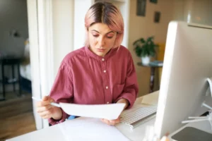 Mujer revisando documentos de facturación en su computadora mientras gestiona la cancelación de una factura electrónica