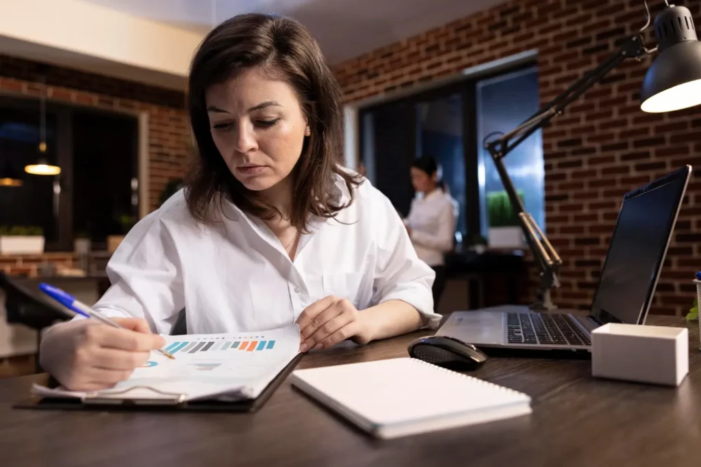 Mujer revisando reportes financieros relacionados con deducciones contables no fiscales en su escritorio