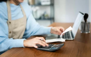 Persona calculando montos y revisando factura antes de emitir CFDI en computadora