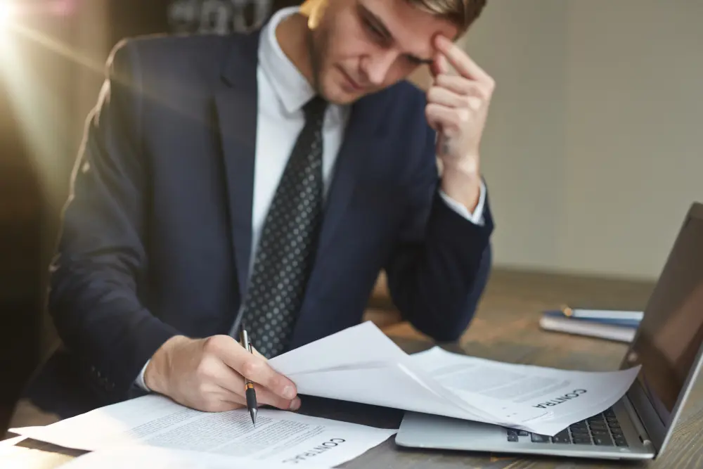 Hombre revisando documentos contables con preocupación por posibles delitos fiscales